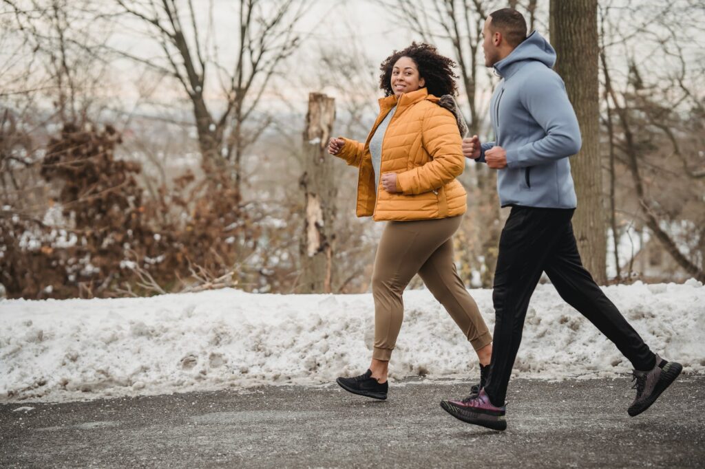 cheerful black couple jogging in snowy park